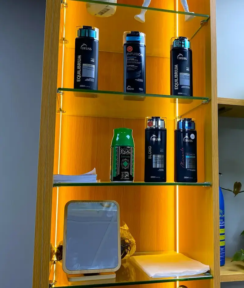 professional hair care products displayed on illuminated shelf in barber shop at Kings Afro Barbershop JVC Dubai