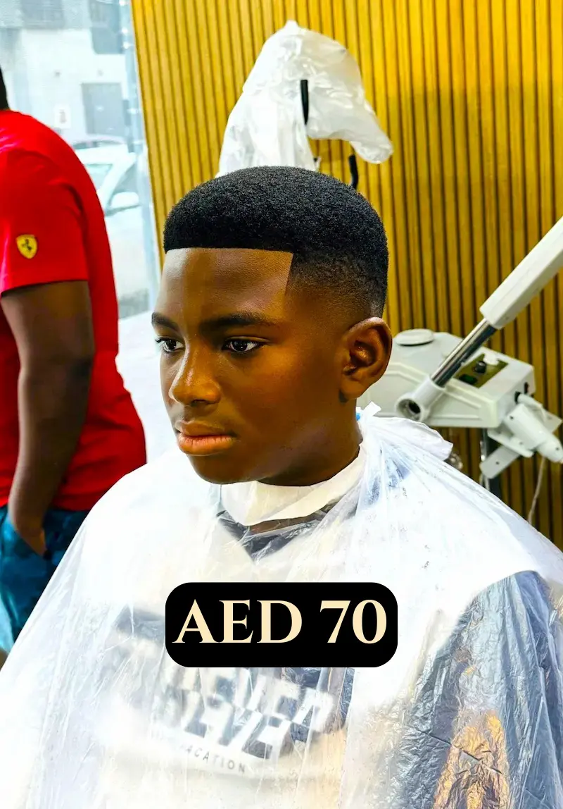 young boy after a fresh haircut sitting in a barber chair with a clean low fade and sharp lineup inside a modern barbershop