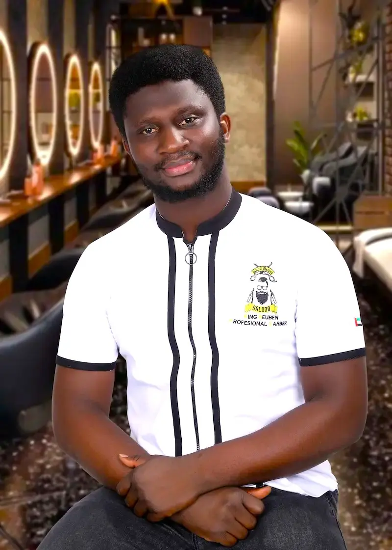 barbershop owner sitting inside a modern salon with stylish interior and warm lighting, smiling at the camera